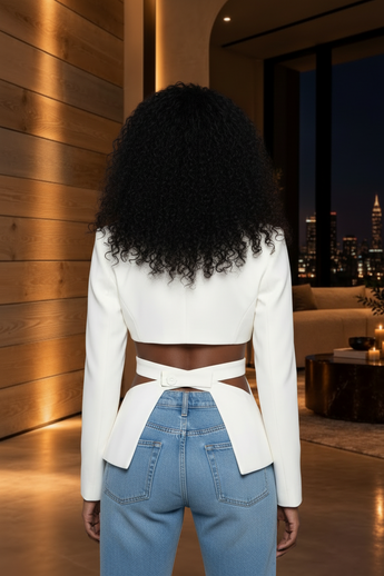 Back view of a woman wearing a Bleu Hanger ivory cropped blazer with waist cutouts and button-tab detail.